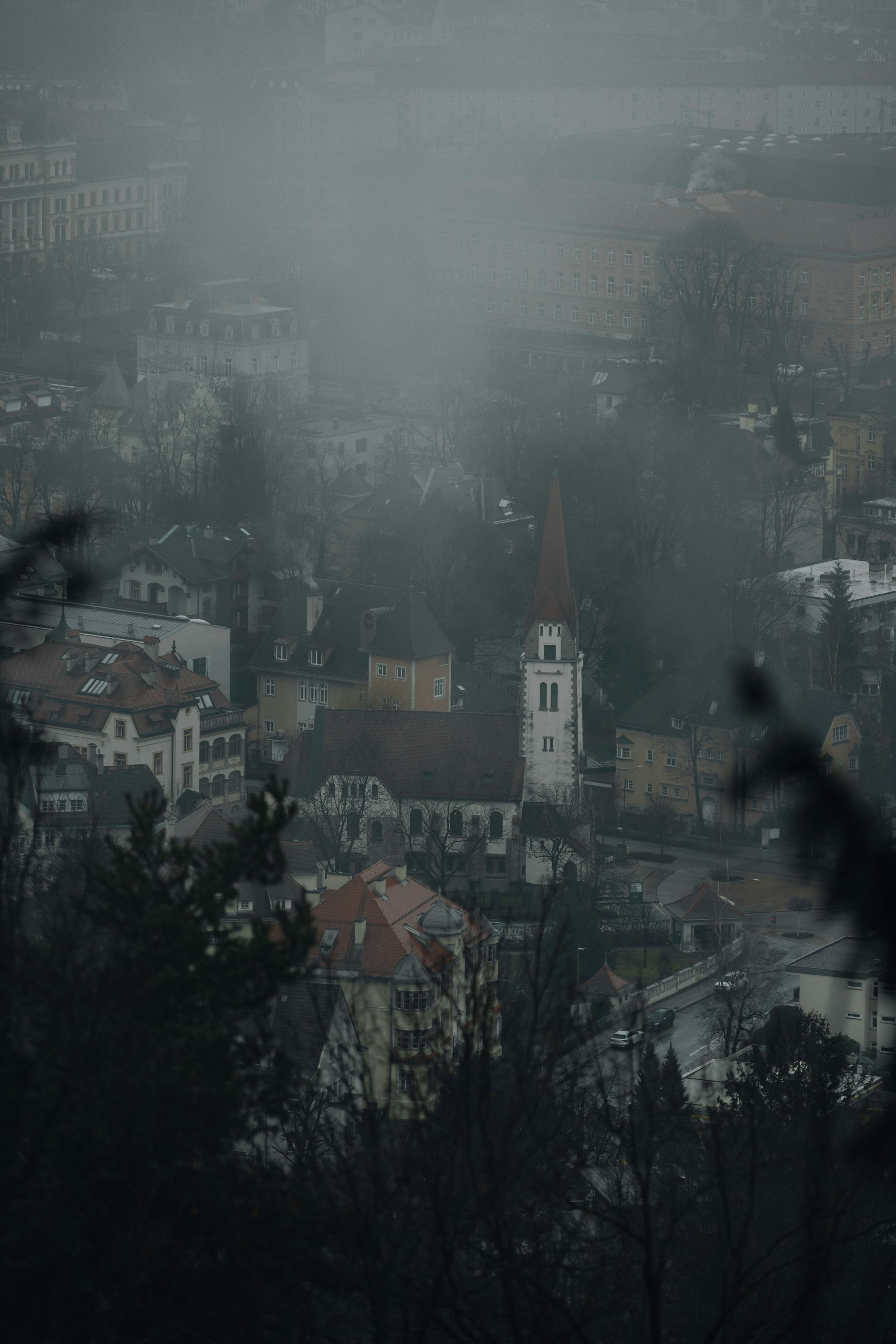 A foggy view of a city with a clock tower by Florian Schindler
