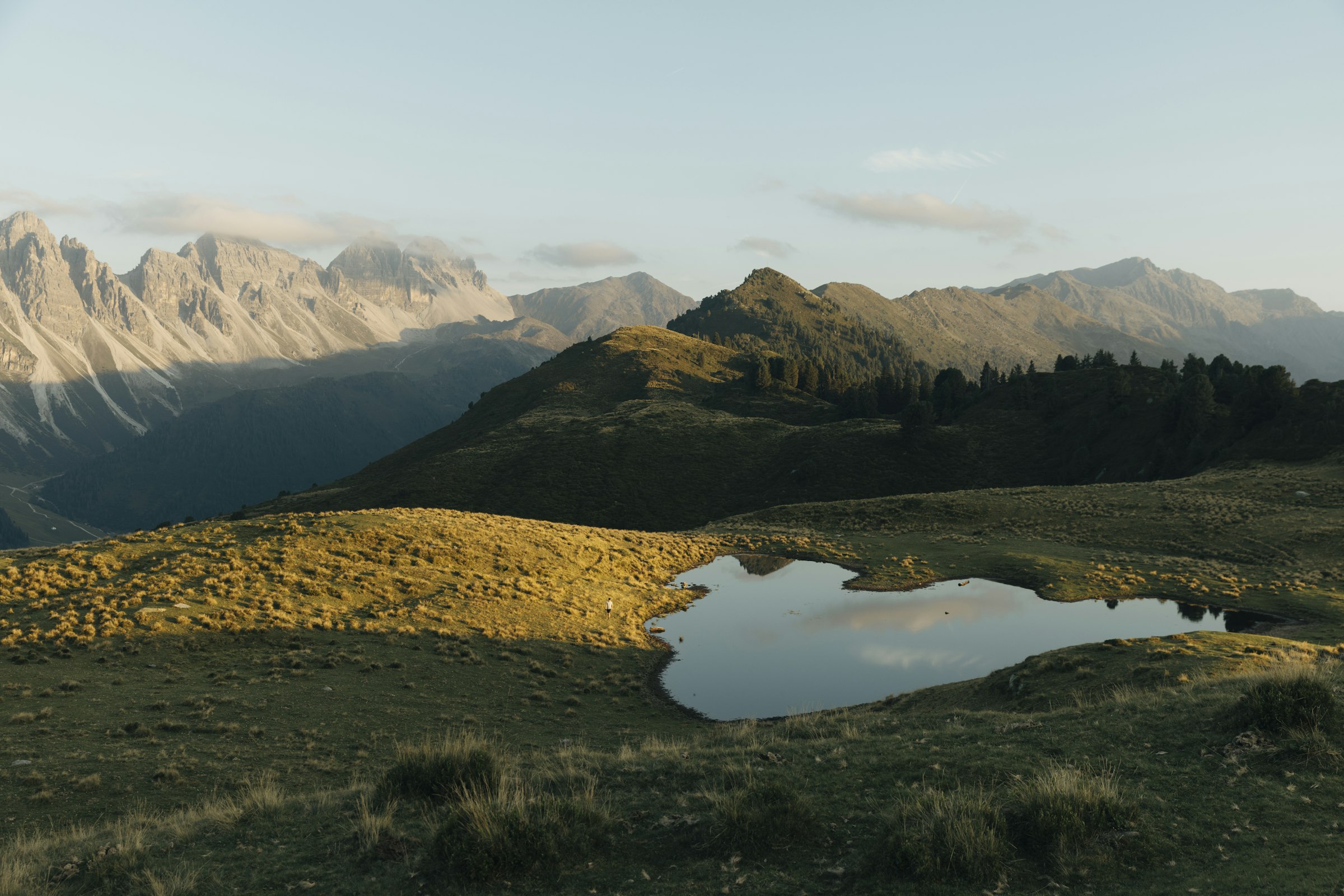A small lake in a grassy mountain landscape at sunset by Florian Schindler