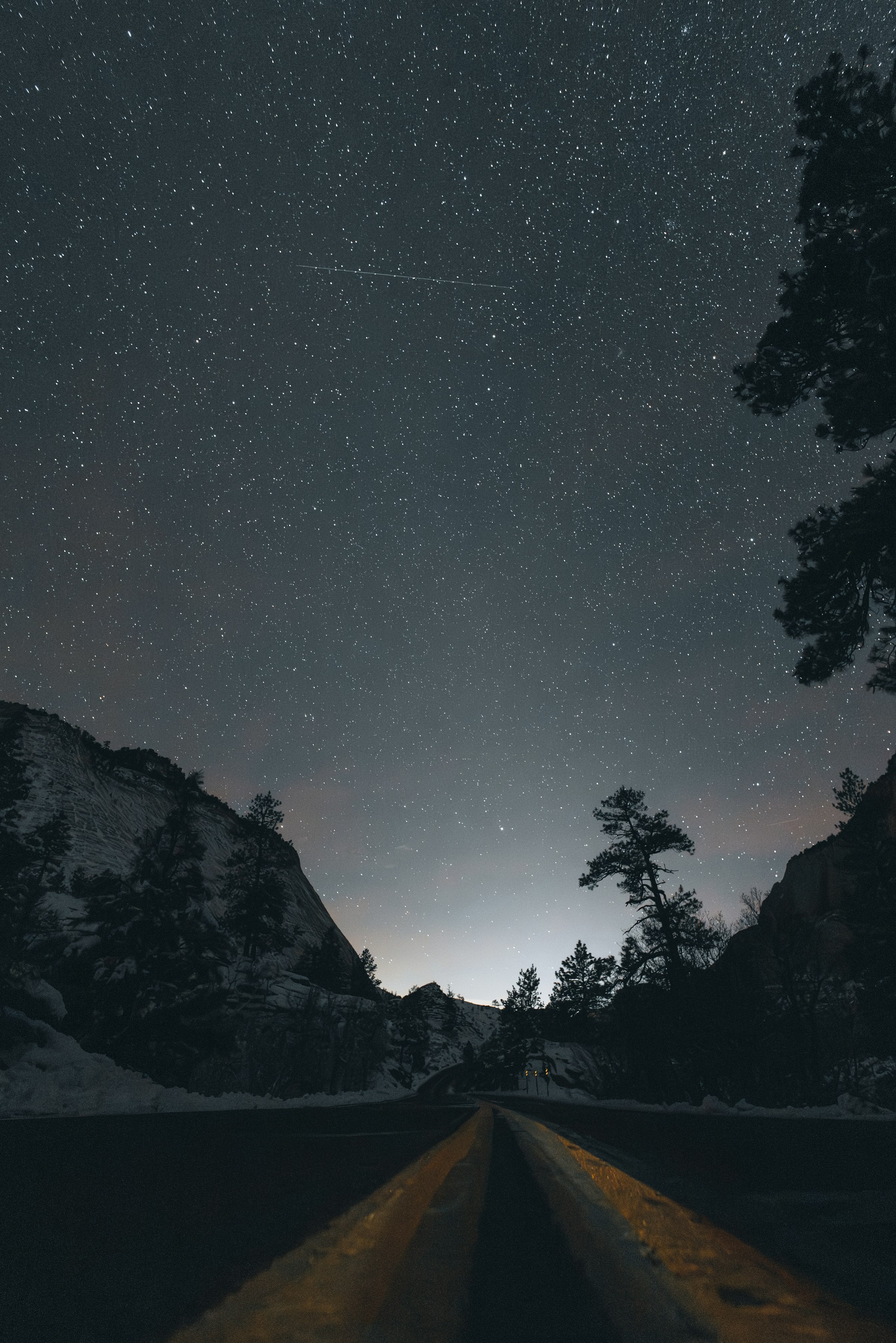 A starry night sky over a road between mountains by Florian Schindler