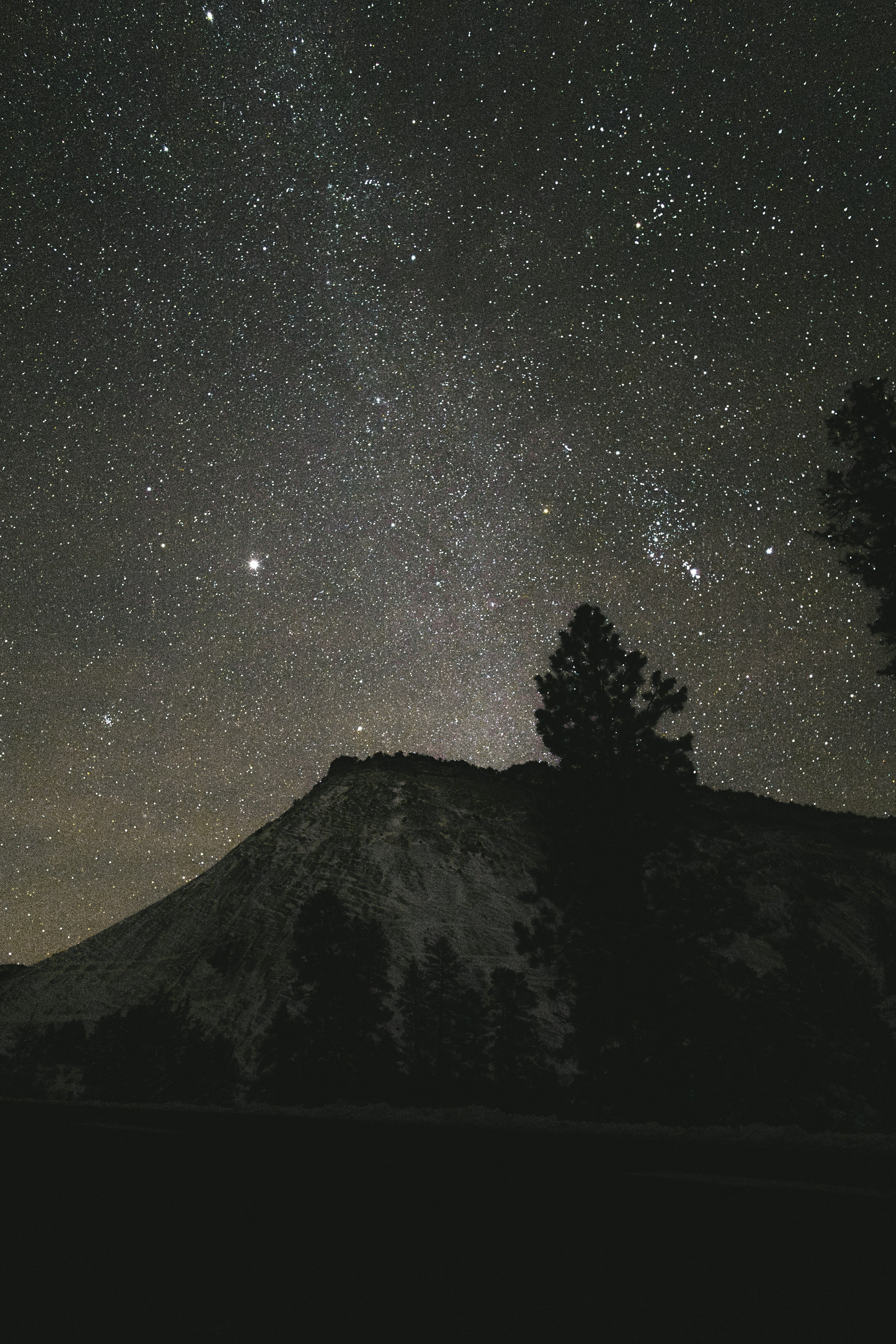 Starry night sky over a silhouetted mountain peak by Florian Schindler