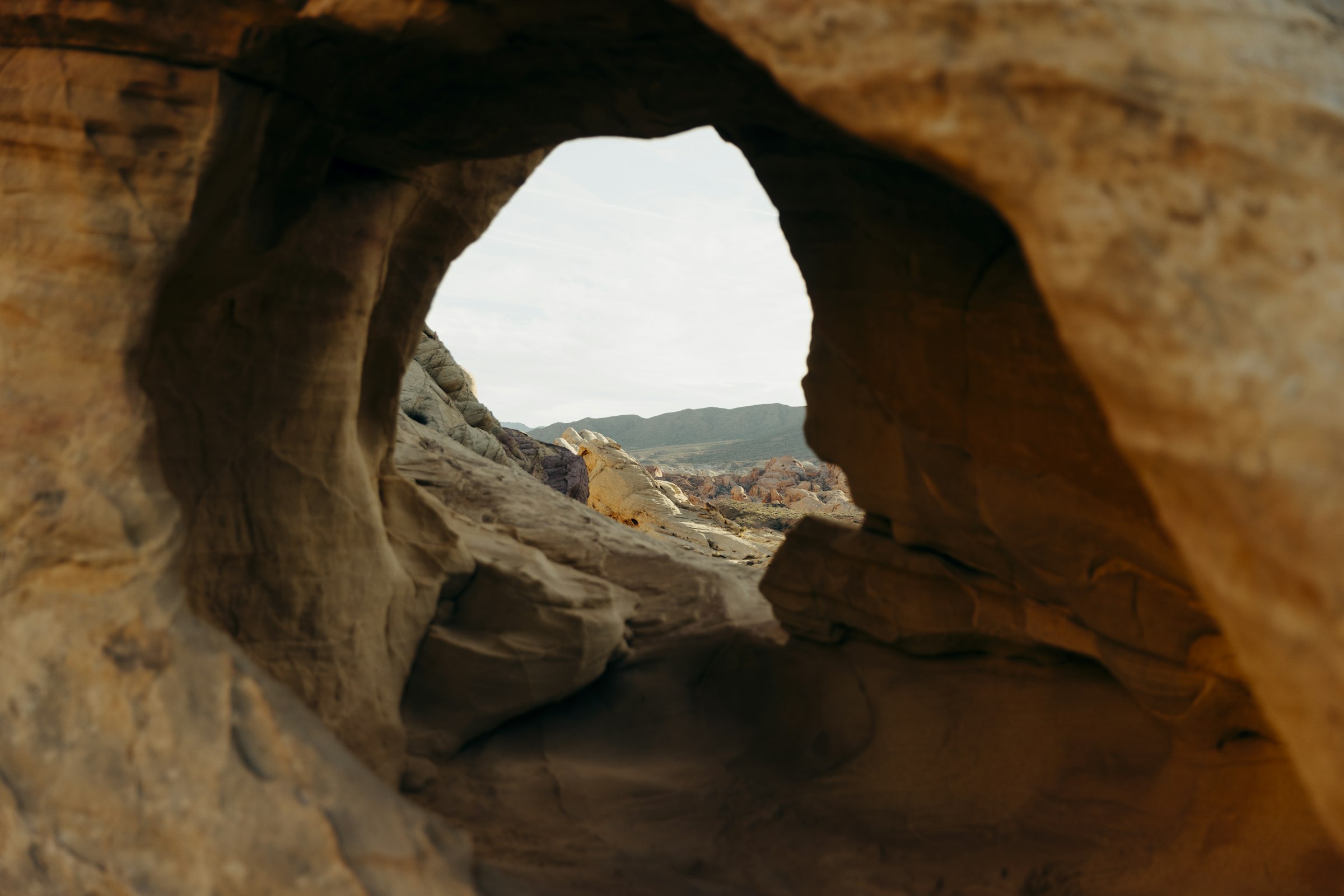 View through a rock arch at a desert landscape by Florian Schindler