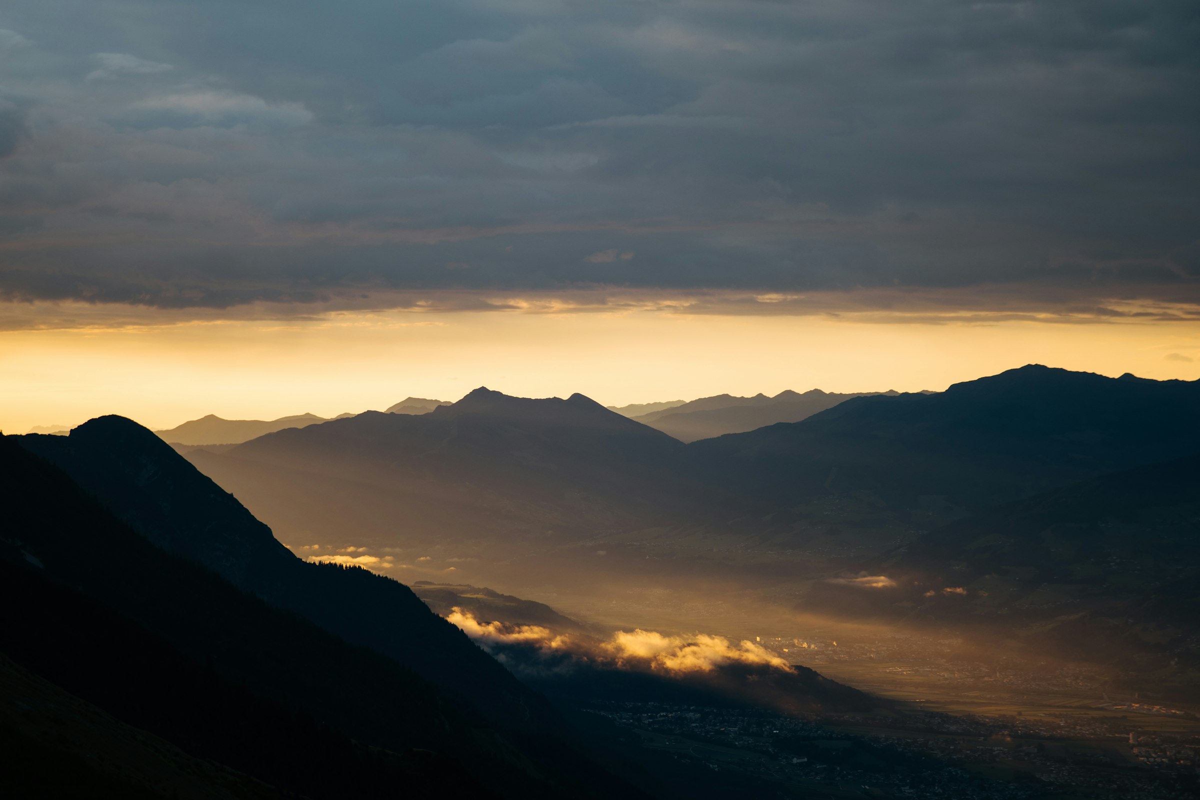 Dramatic sunset over silhouetted mountain peaks by Florian Schindler