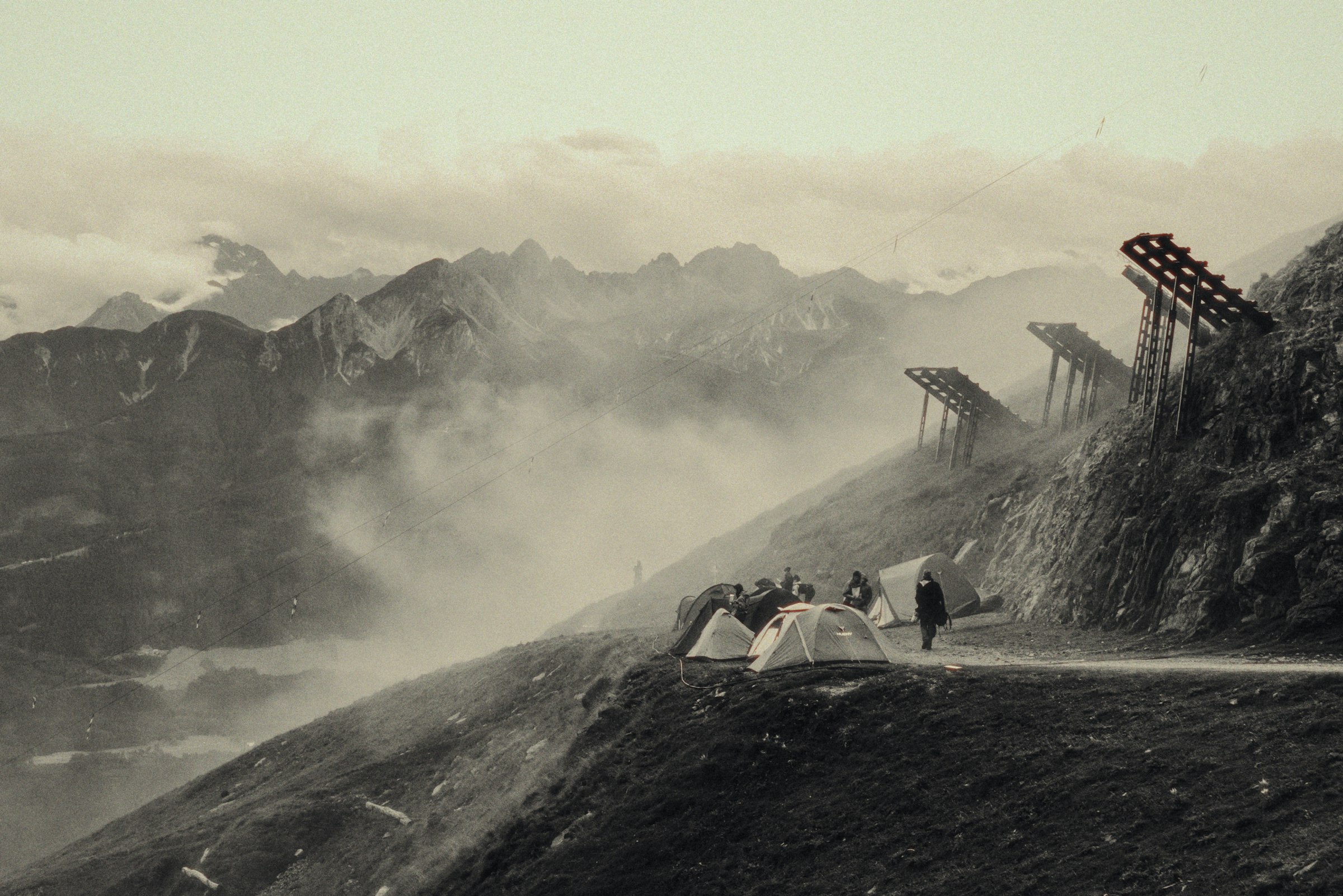 Misty mountain landscape with tents and wooden structures by Florian Schindler