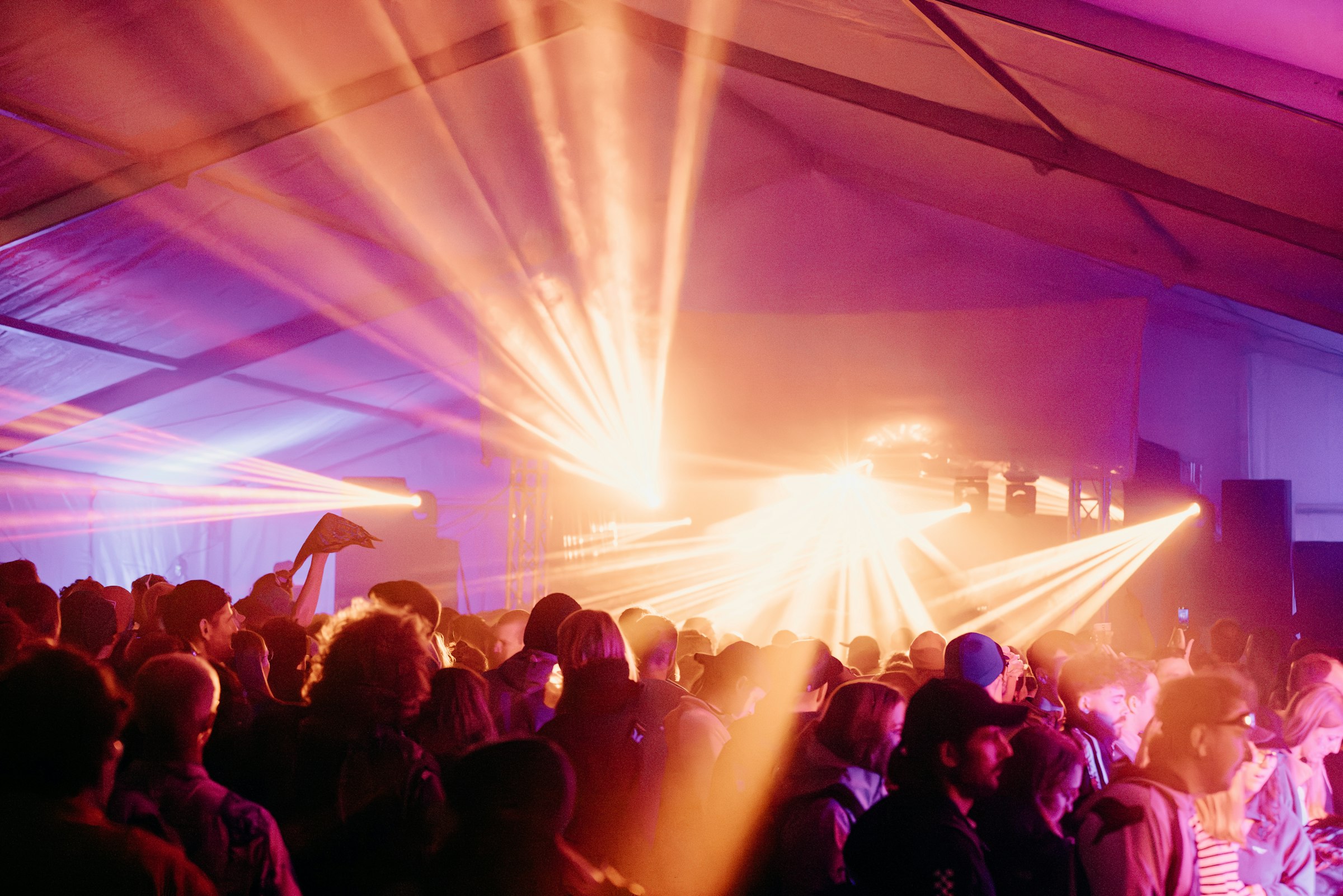 People dancing under vibrant orange and purple stage lights by Florian Schindler