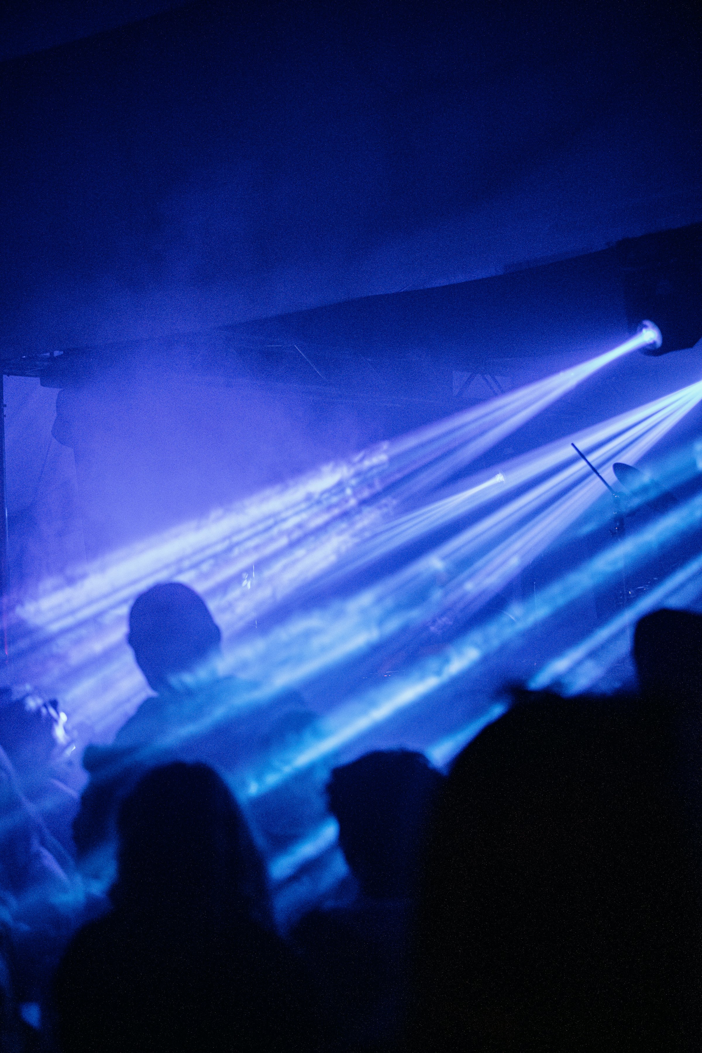 Silhouetted crowd enjoying blue light beams at a concert by Florian Schindler