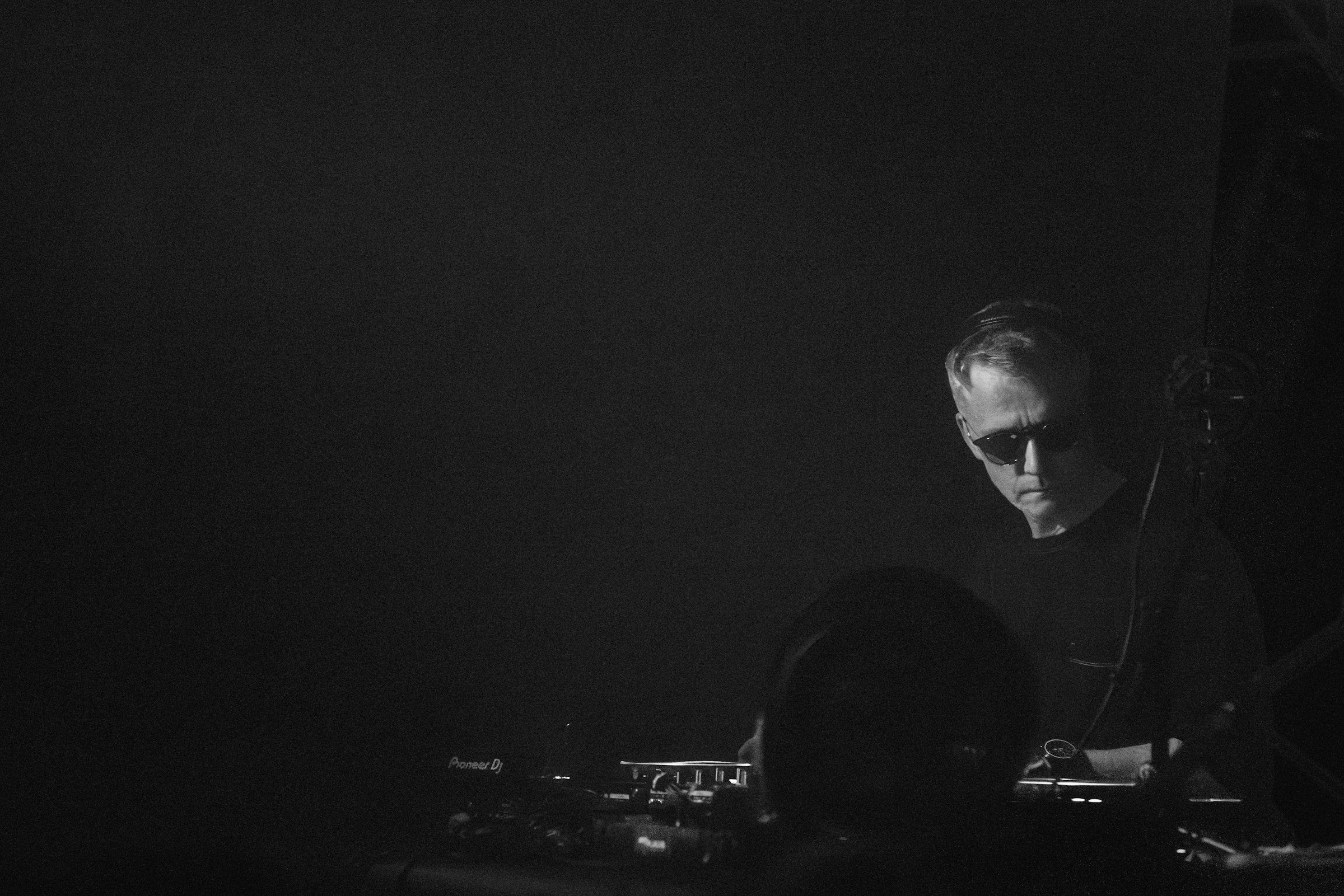 A man focused on music equipment in a dark monochrome scene by Florian Schindler